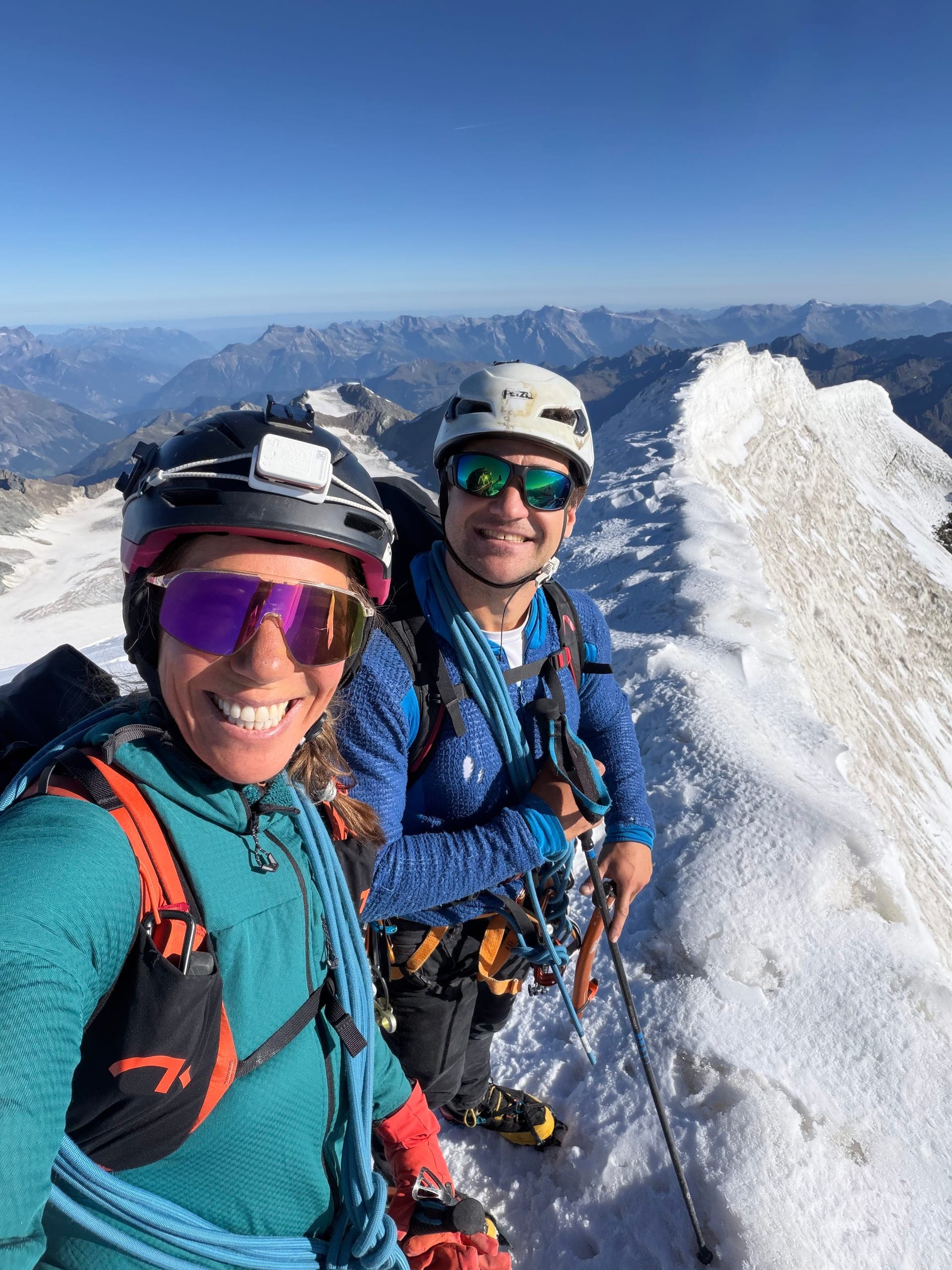 Deux alpinistes en selfie sur une arête de neige du Grand Combin, ciel bleu derrière eux