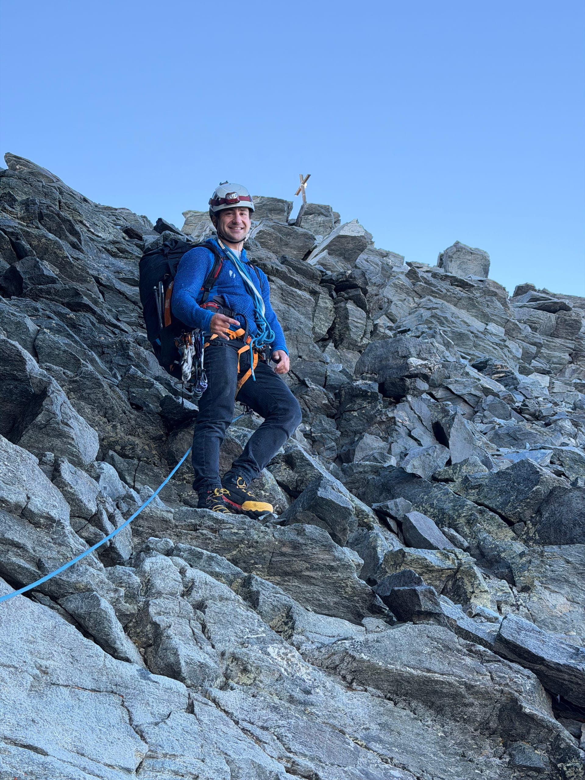Un alpiniste encordé sur une arête rocheuse du Grand Combin, ciel bleu dégagé
