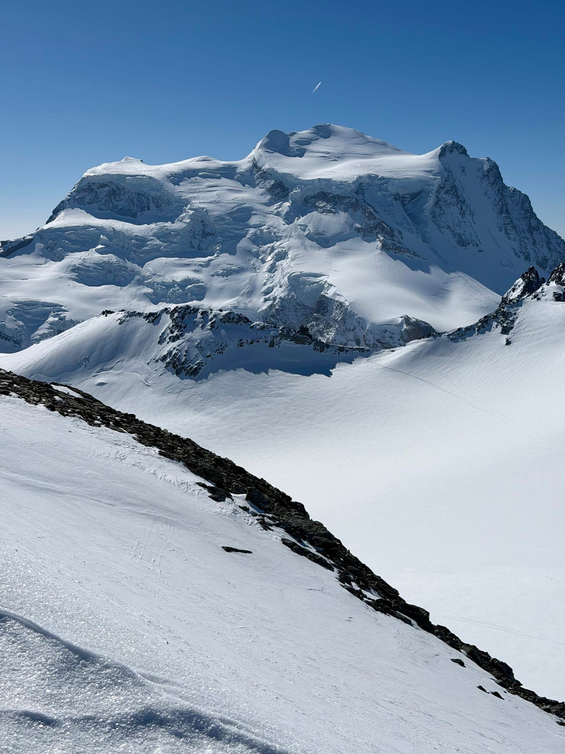 Sommet enneigé du Grand Combin et pente de neige sous un ciel bleu